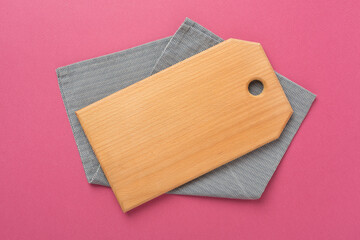 Cutting board with napkin on color background, top view