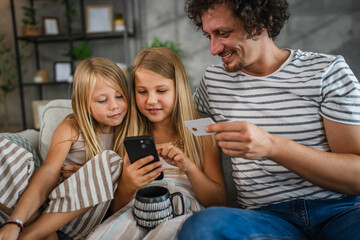 daughters and dad buy online on mobile phone with credit card at home