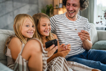 daughters and dad buy online on mobile phone with credit card at home