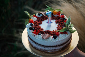 A delicious red velvet cake for a first birthday, decorated with fresh fruit (physalis, blueberries, raspberries, currants, and blackberries). Finished with red velvet crumbs and milk chocolate.