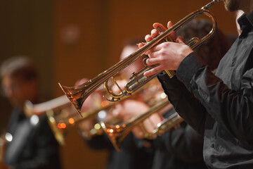 Close-up of a trumpet player performing in a brass ensemble, focusing on the musician's hands and...