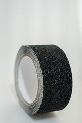 Roll of black adhesive tape on white background
Close-up of a single roll of black adhesive tape with a textured surface, placed against a clean white background.
