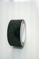 Roll of black adhesive tape on white background
Close-up of a single roll of black adhesive tape with a textured surface, placed against a clean white background.
