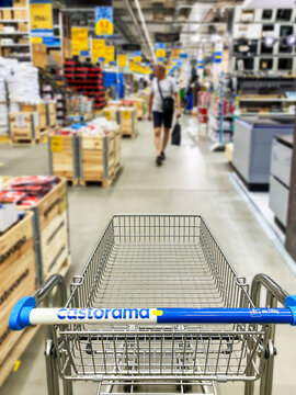 Pusty koszyk, w&oacute;zek sklepowy w supermarkecie, rozmazane tło, wnętrze sklepu, supermarketu, w&oacute;zek na zakupy, p&oacute;łki sklepowe z produktami. Hipermarket Castorama. Warszawa, CH Wola Park. Miejsce na tekst
