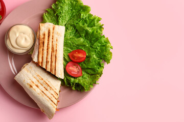Plate with tasty shawarma and lettuce on pink background