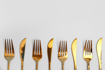 Golden forks and knives on white background, closeup