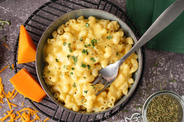 Bowl of tasty Italian pasta with Cheddar cheese on grunge background