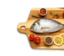 Wooden board of raw dorado fish with lemon and tomatoes on white background