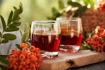 Two glasses of herbal syrup with fresh wild orange rowanberry