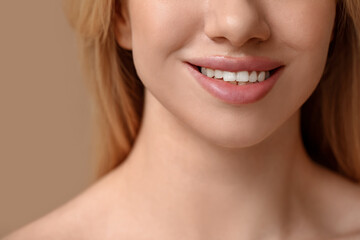 Obraz premium Smiling young woman with beautiful lips on brown background, closeup