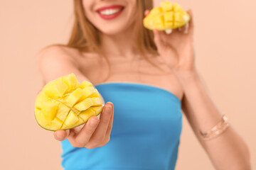 Young woman with cut sweet mango fruit on beige background