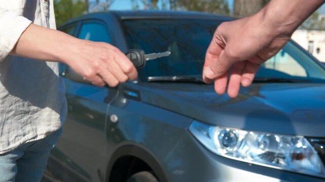 Lady take key from car salesman. A man give control key to woman after buying a car at parking.
