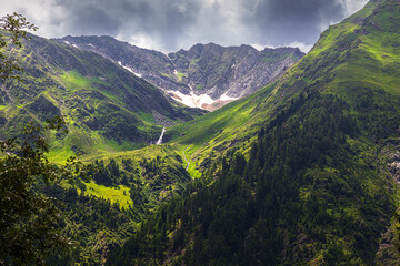 Obraz premium Schöne berge mit schnee und grünen gras mit wasserfall und schönen himmel