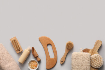 Composition with wooden guasha body massage tool, bowl of sea salt and scoop on grey background