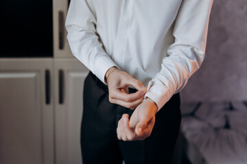 Groom adjusting his cufflinks, preparing for his wedding day, focusing on details and elegance