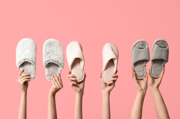 Female hands holding different women's slippers on pink background