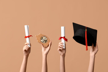 Female hands with graduation hat, piggy bank and diplomas on beige background