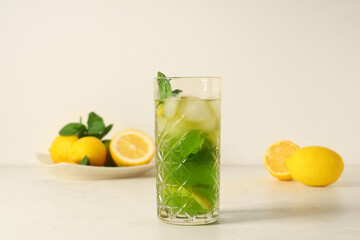 Glass of lemonade with lemon and mint on white background