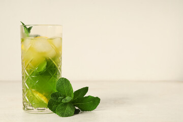 Glass of lemonade with lemon and mint on white background
