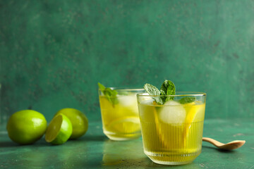 Glasses of tasty lemonade with lemon and mint on green grunge background