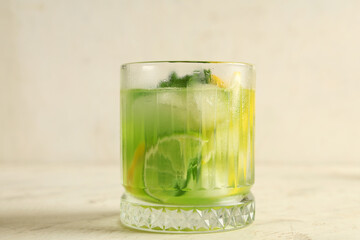 Glass of tasty lemonade with lime slices and mint on white background