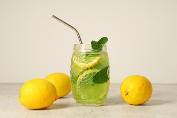 Glass of tasty lemonade with lemons and straw on white background
