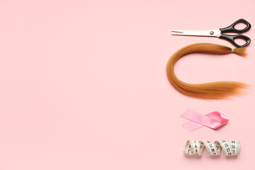 Red hair strand for donation with awareness ribbon, measuring tape and scissors on pink background