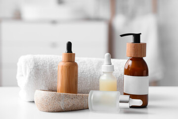 Bottles of cosmetic products, towel and stone soap box on table in bathroom, closeup