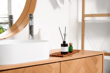 Sink, aroma diffuser and bottles of cosmetic products in bathroom