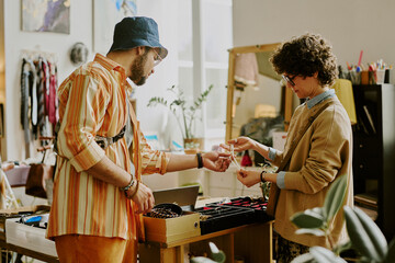 Shopkeeper assisting customer in trendy boutique while discussing different types of jewelry pieces displayed Services offered in stylish decorated space with unique accessories