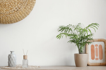 Aroma diffuser, vase, frame and houseplant on chest of drawers in living room