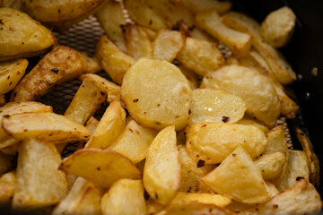 Golden crispy roasted potato wedges close-up. A close-up of golden, crispy roasted potato wedges, seasoned with herbs and spices, served on a white plate.

