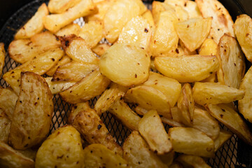 Golden crispy roasted potato wedges close-up. A close-up of golden, crispy roasted potato wedges, seasoned with herbs and spices, served on a white plate.


