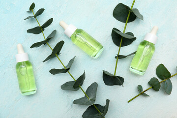 Bottles of eucalyptus essential oil and twigs on blue grunge background