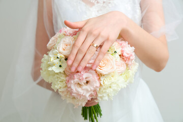 Beautiful bride with wedding bouquet on light  background, closeup