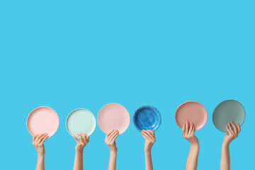 Hands holding empty plates on blue background
