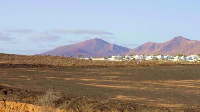 Barren east landscape with no life vegetation desert mountains blue clear sky white houses clouds Yaiza Lanzarote Canary Islands no people background documentary planet dimension aliens exploration 
