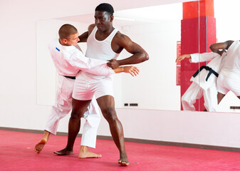 African-american man exercising throws with his trainer in kimono during judo training.