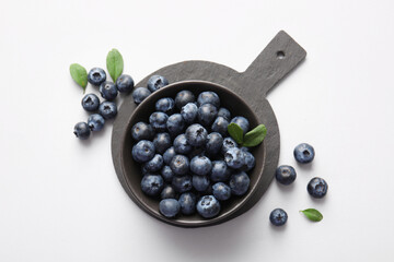 Cutting board and bowl with fresh ripe blueberry on white background