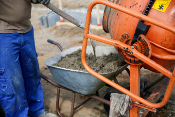Constriction worker making concrete in an orange mixer