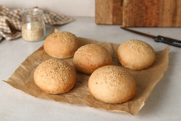 Baking paper of fresh buns with sesame seeds on white background