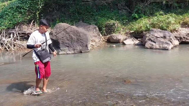 a man who was doing his fishing hobby using casting techniques in a river in the Magelang area, Central Java, Indonesia