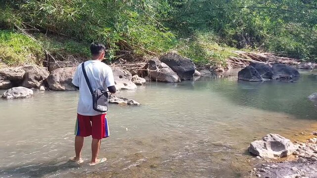 a man who was doing his fishing hobby using casting techniques in a river in the Magelang area, Central Java, Indonesia