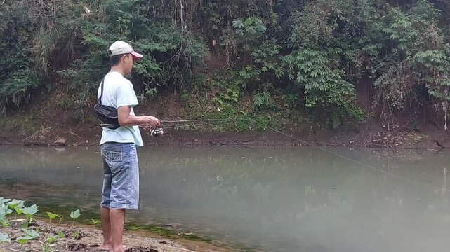 a man who is fishing using a casting technique in a river in the Magelang area, Central Java, Indonesia

