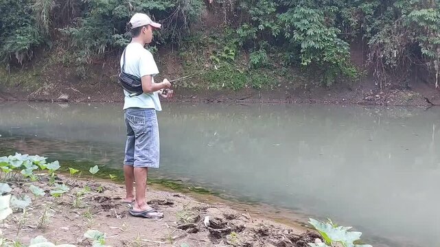 a man who is fishing using a casting technique in a river in the Magelang area, Central Java, Indonesia
