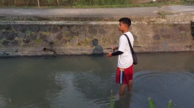 a man who was doing his fishing hobby using casting techniques in a river in the Magelang area, Central Java, Indonesia