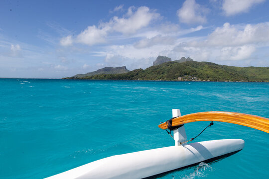 A boat floats on vibrant azure blue ocean water  near the island of Bora Bora