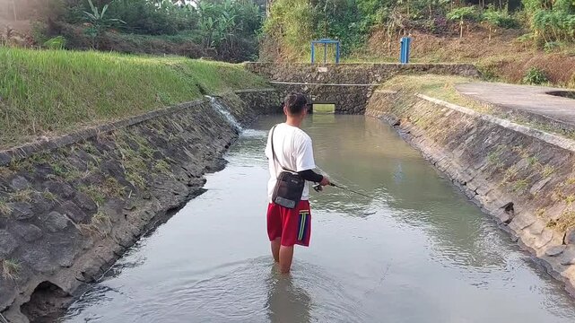a man who was doing his fishing hobby using casting techniques in a river in the Magelang area, Central Java, Indonesia