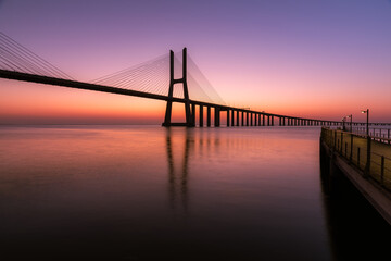 Dawn on the river with a large cable-stayed bridge. Vasco da Gama Bridge in Lisbon, Portugal	