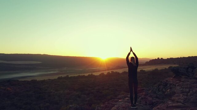 Nature sunset, yoga silhouette and person meditate for wellness, spiritual stress relief or healing aura, soul or chakra energy. Cliff, back and pilates yogi meditation for mental health and mindset